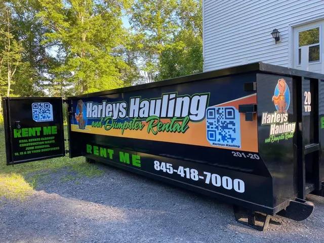 Black Harley's Hauling dumpster trailer with green and orange branding parked beside a house