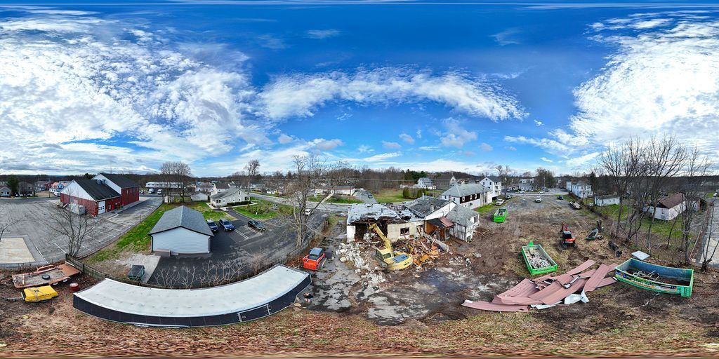 Aerial view of a rural village with damaged homes and debris under a blue sky