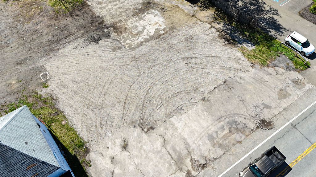 Aerial view of a gravel lot beside a road, with a white van parked near the top right.