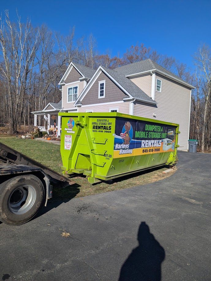 Bright green dumpster on a driveway beside a house on a sunny day