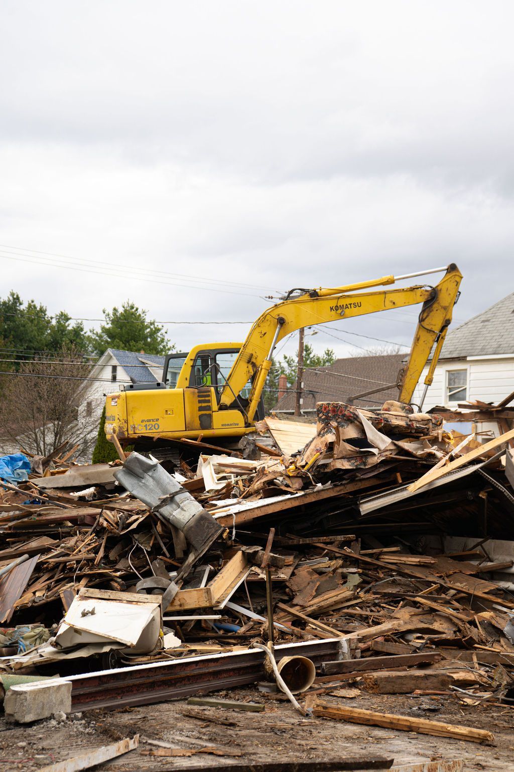 Yellow excavator amid debris clearing a demolished building site
