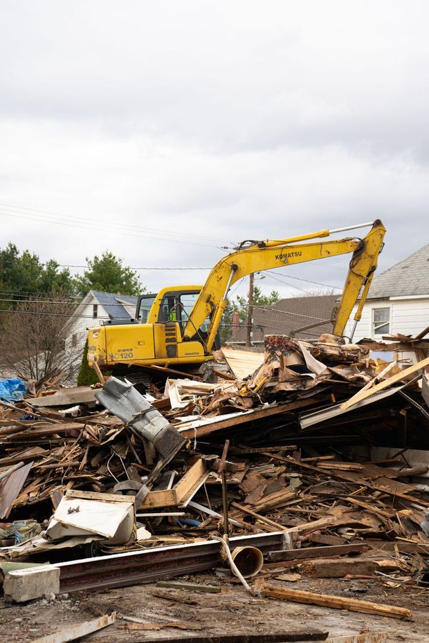 Yellow excavator amid debris at a demolition site