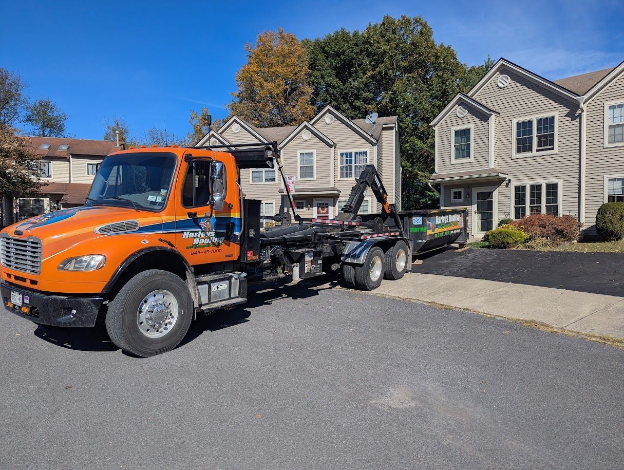 Orange tow truck parked in front of beige apartment buildings on a sunny street