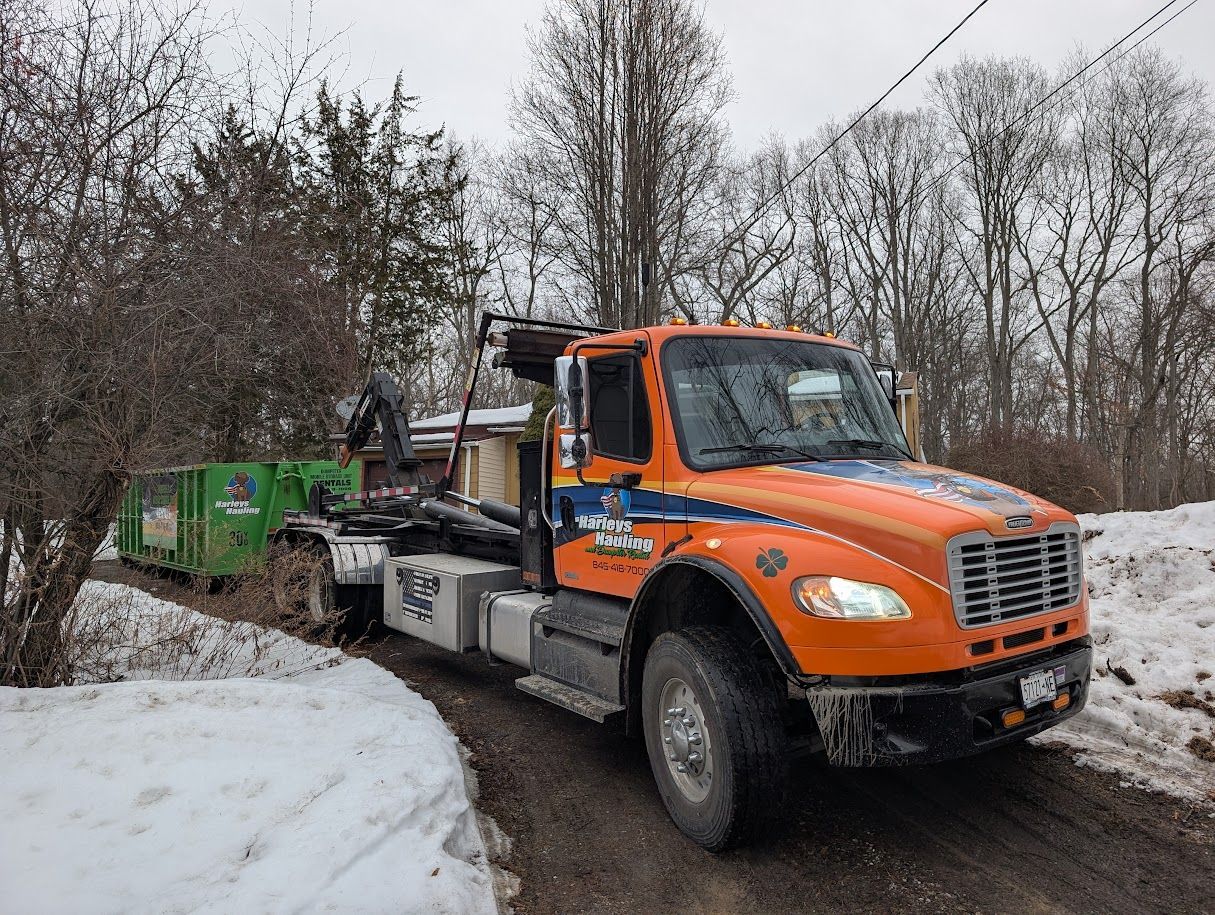 Orange tow truck pulling a green vehicle on a snowy road in a wooded area