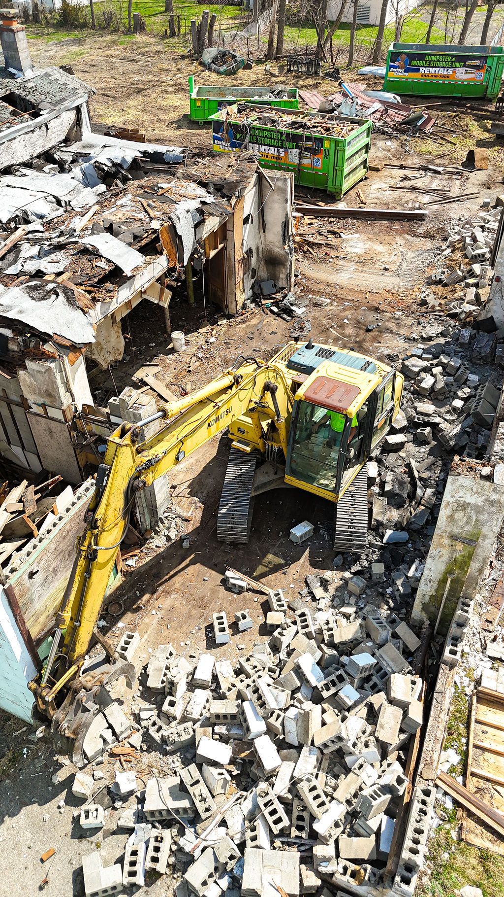 Demolition site with excavators clearing rubble around a partially collapsed brick building