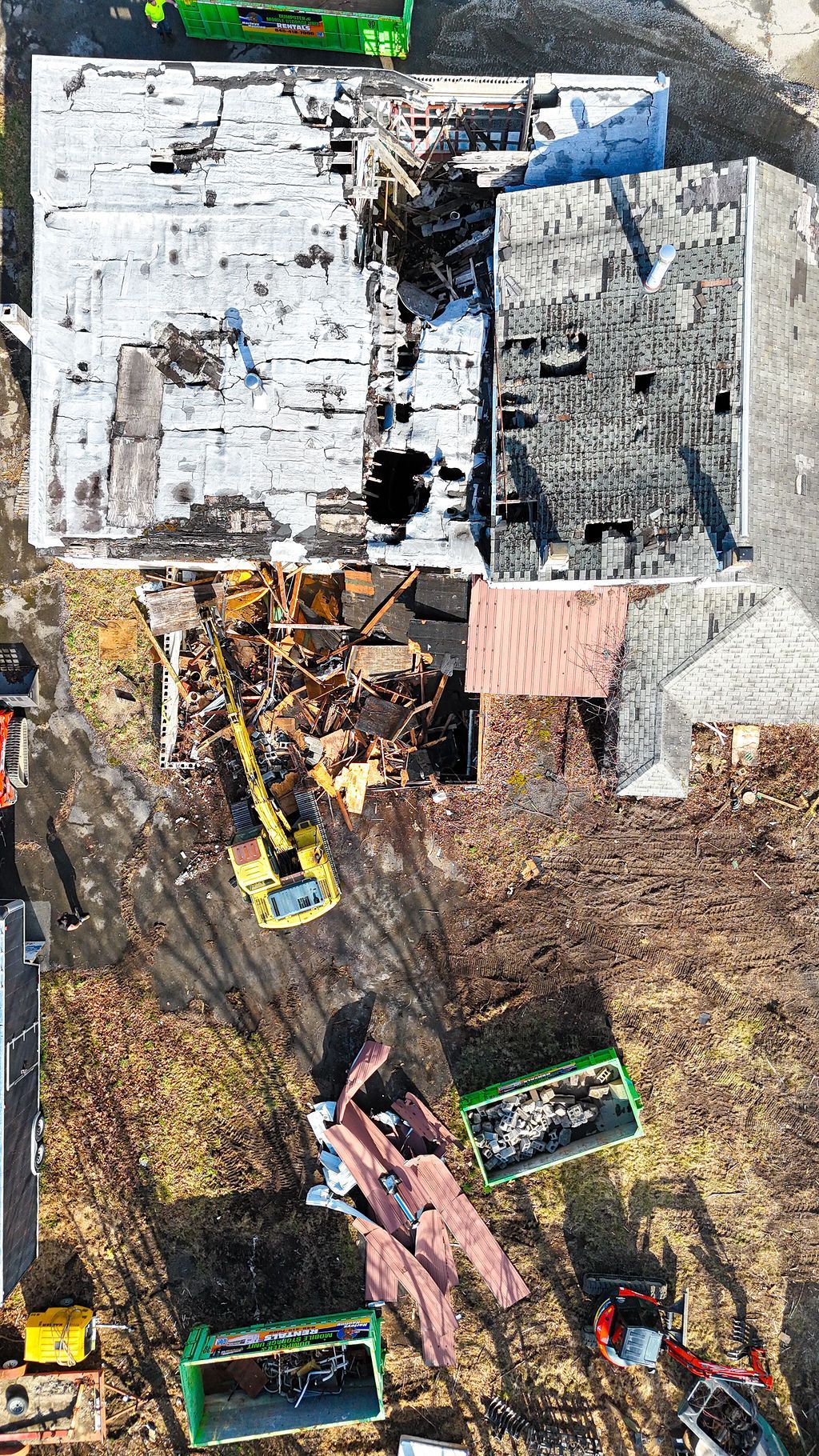 Aerial view of a fire-damaged building with a collapsed roof and scattered debris around it