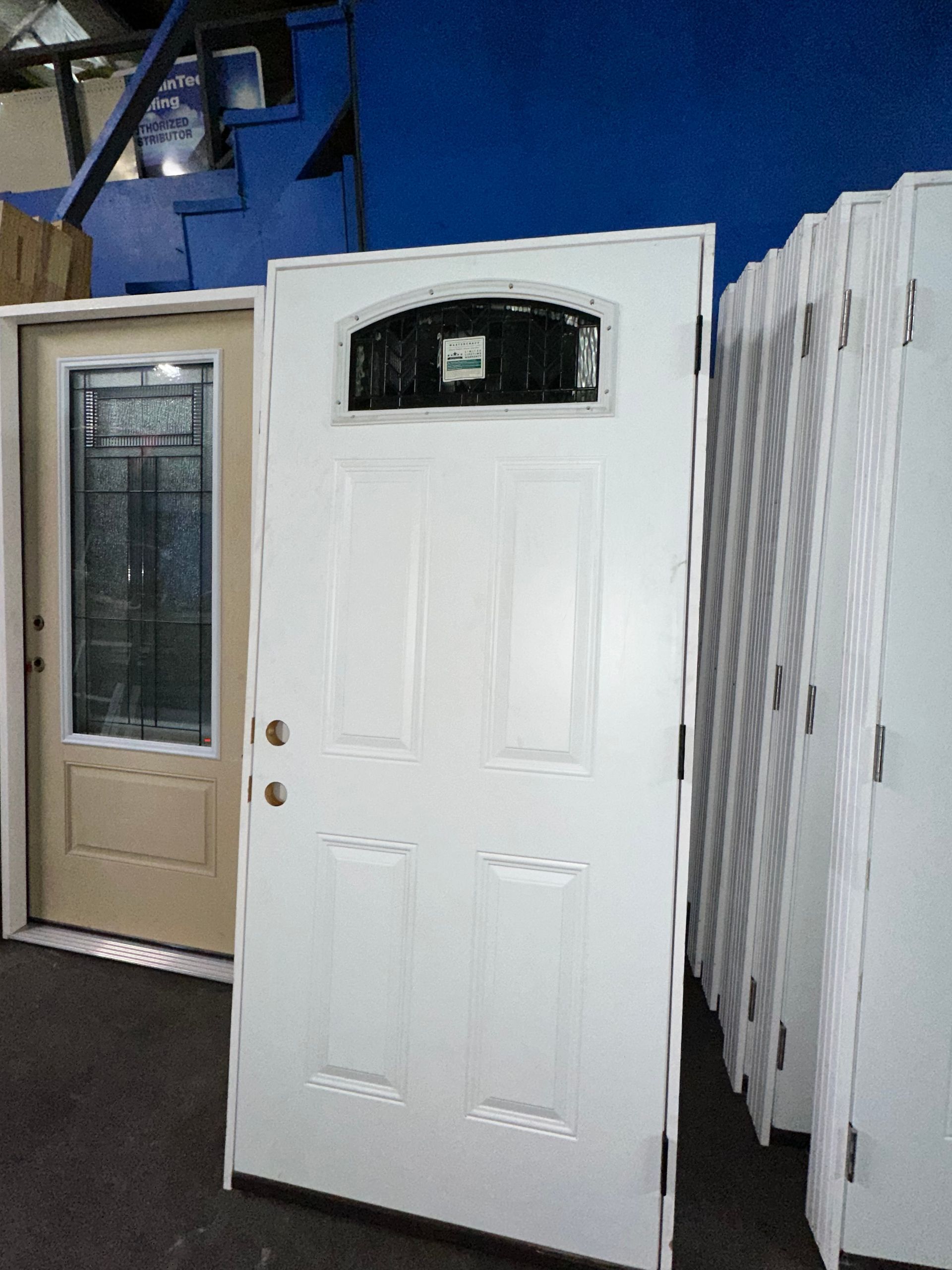 A white door with a small window sits next to a tan door