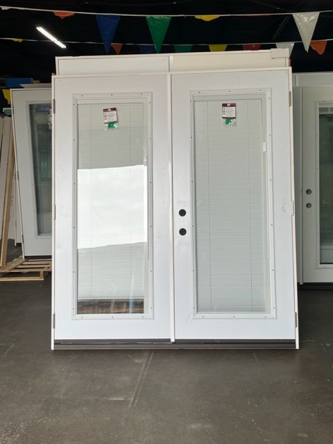A pair of white doors with glass in a room with flags hanging from the ceiling.