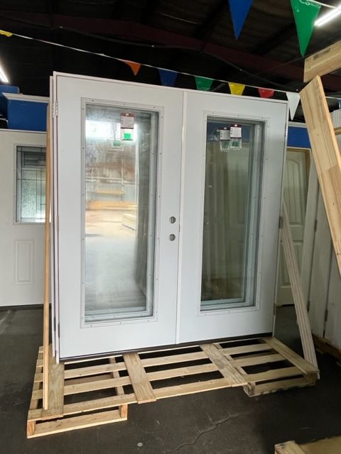 A pair of white doors sitting on top of a wooden pallet.
