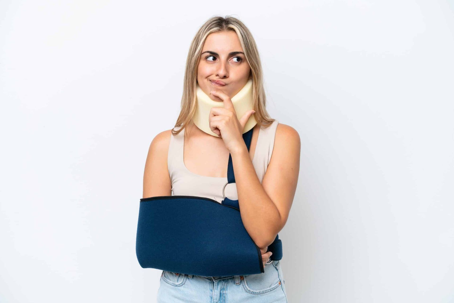 A person wearing a neck brace and a blue arm sling, looking upward thoughtfully with a finger against their chin.
