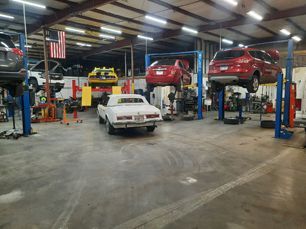 A lot of cars are sitting on lifts in a garage.