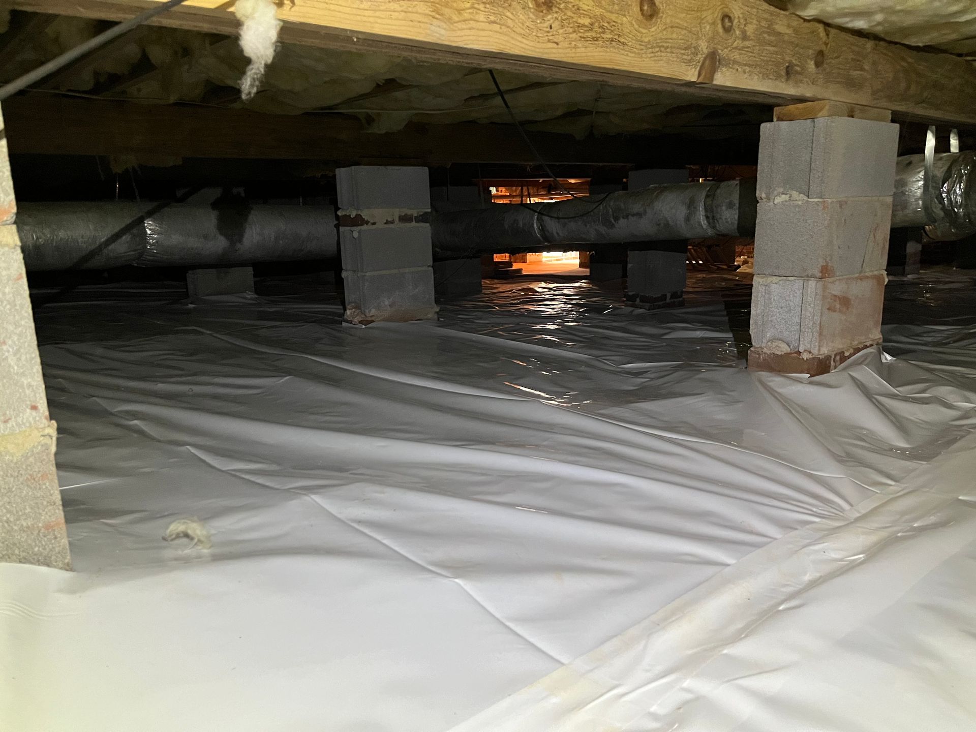 A crawl space with a lot of pipes coming out of it.