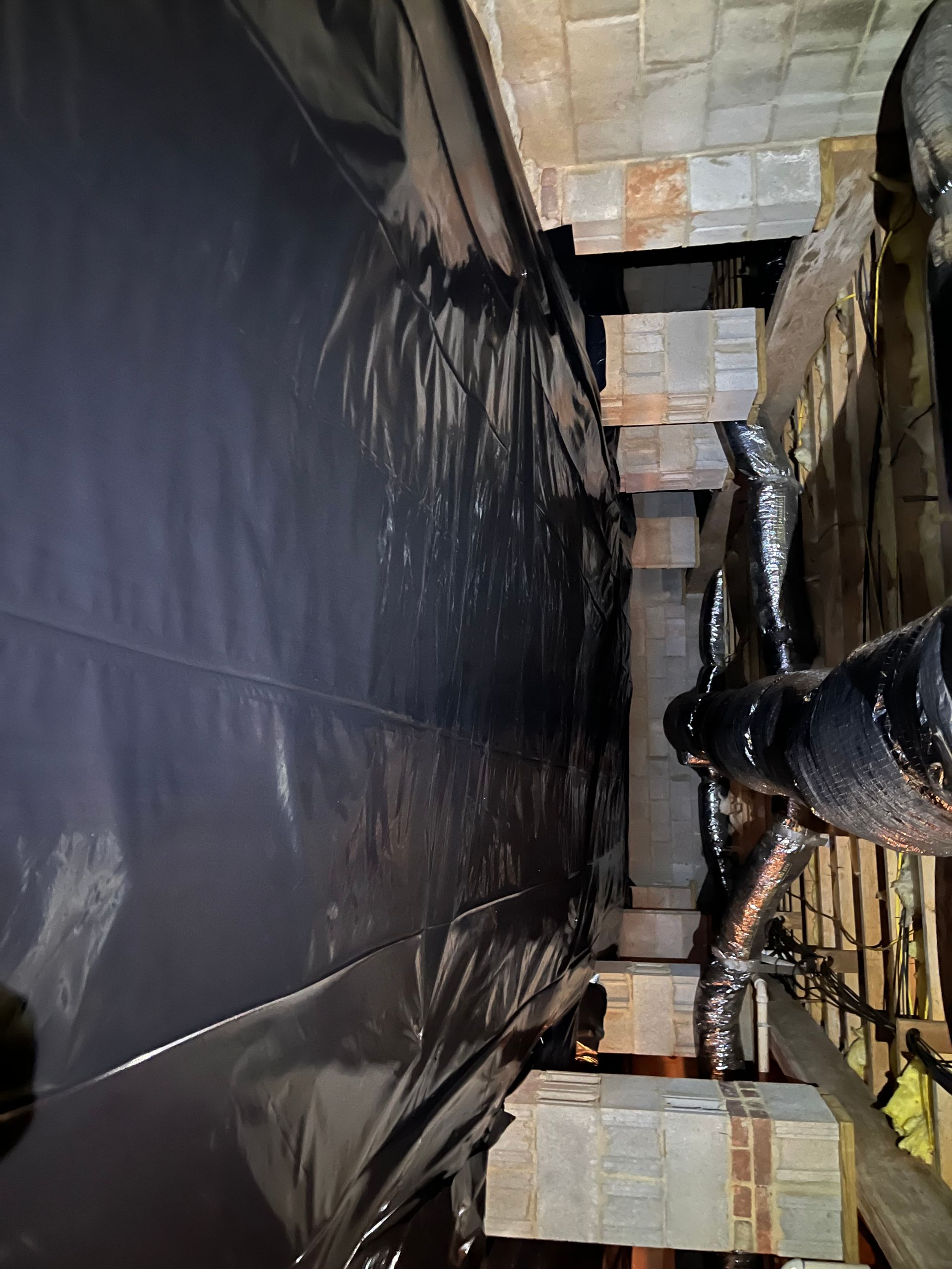 A black tarp is covering a brick wall in a room.