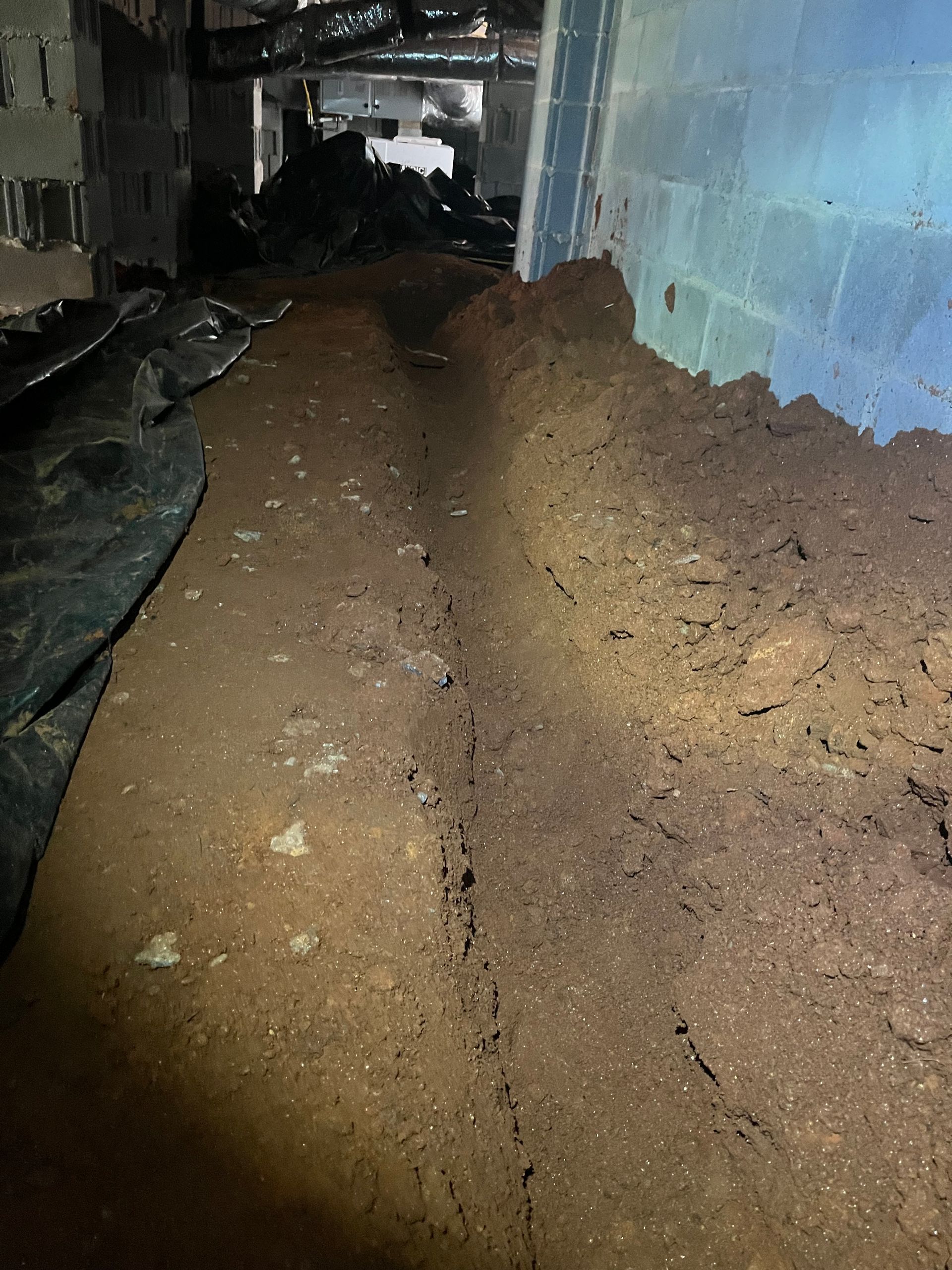 A pile of dirt in a basement next to a brick wall.