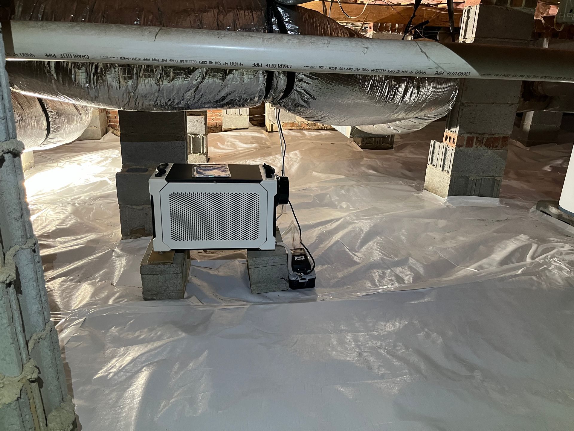 A white box is sitting on top of a white tarp in a basement.