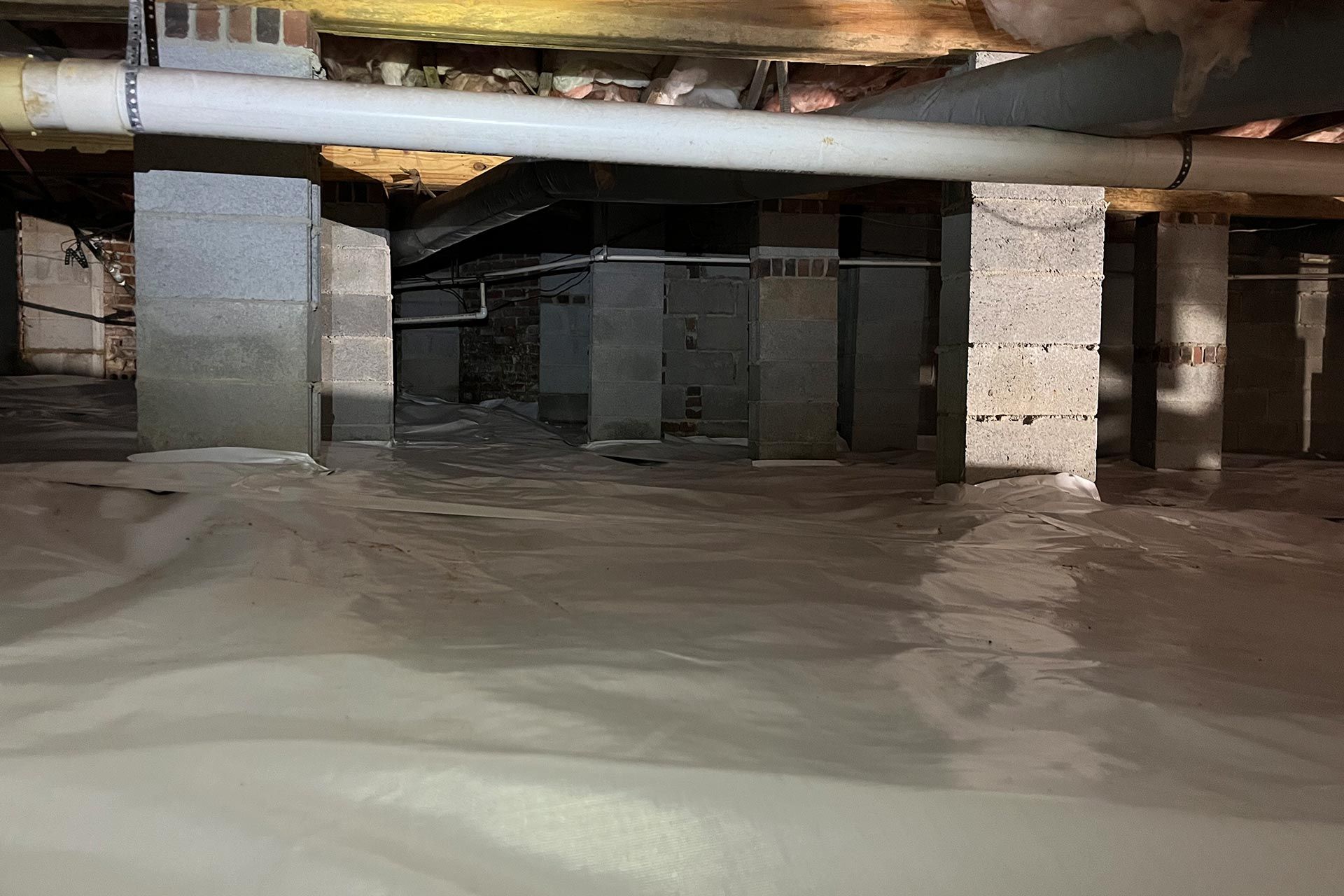 A flooded basement with a lot of water and pipes.