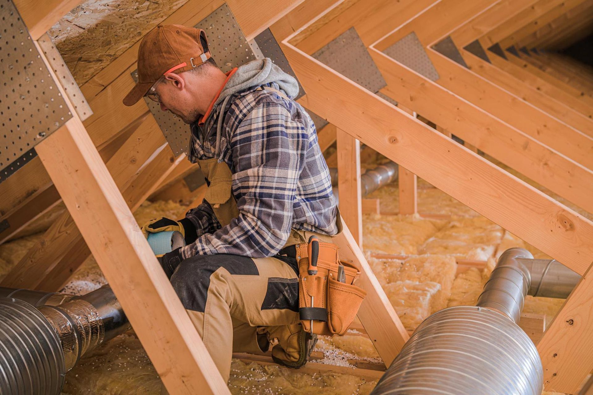 A man is kneeling down in the attic of a house.