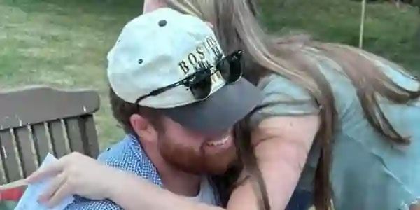 A man wearing a boston hat is hugging a woman.