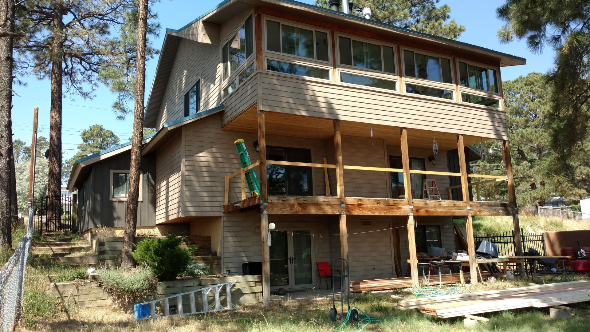 Two-story house with a wooden deck and tan siding set in a wooded area.