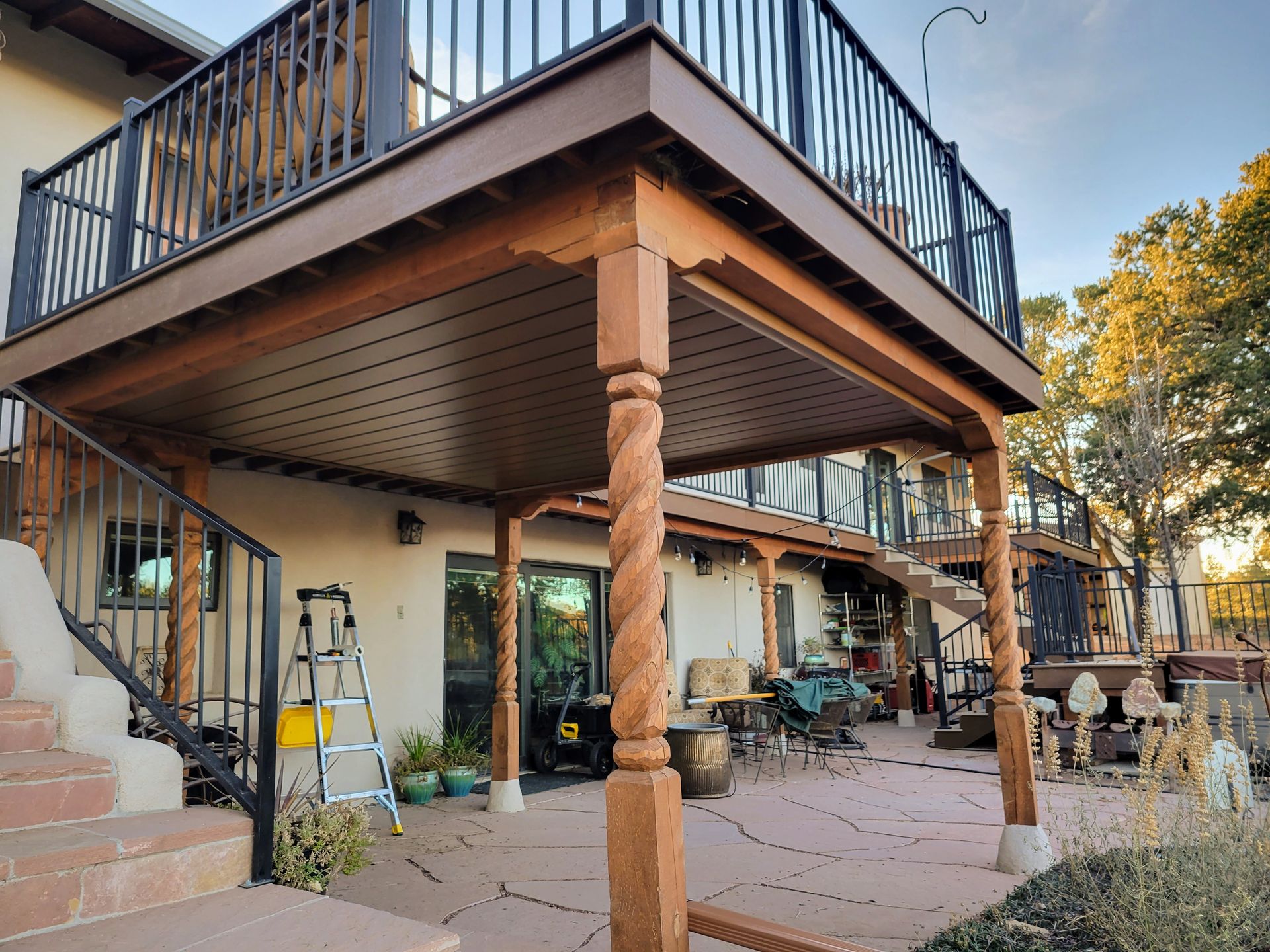 Two-story deck with spiral columns and black railings. Brown decking and stairs lead to upper level.