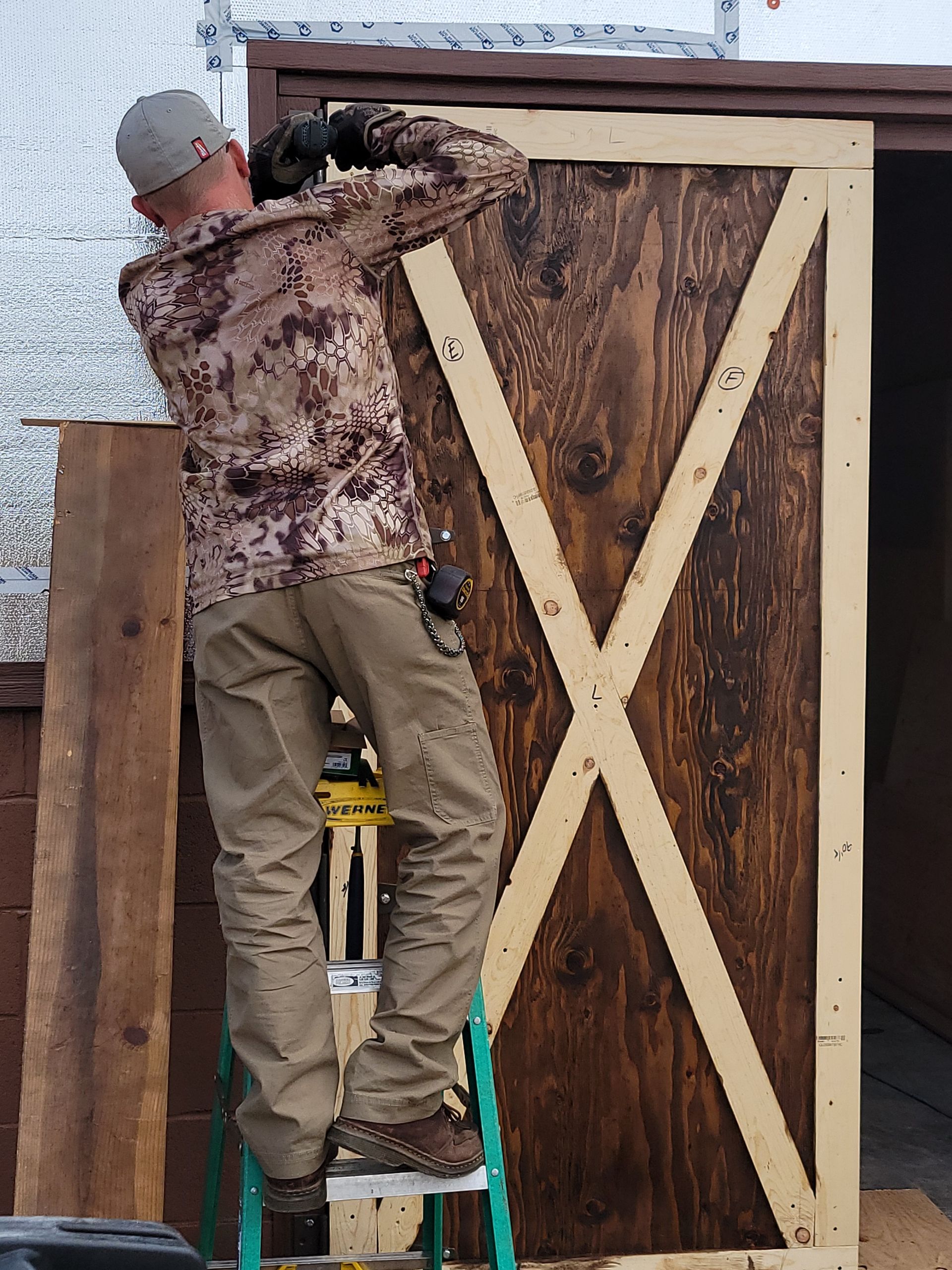 Person on ladder installing wooden door with an 
