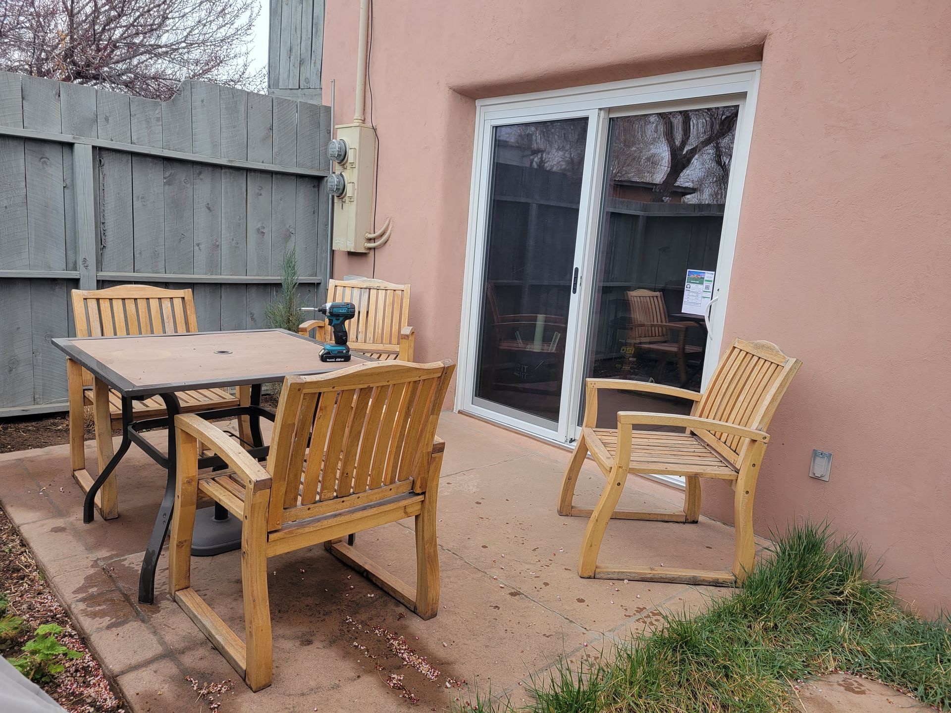 Patio with wooden furniture, sliding glass door, and a pink stucco wall.