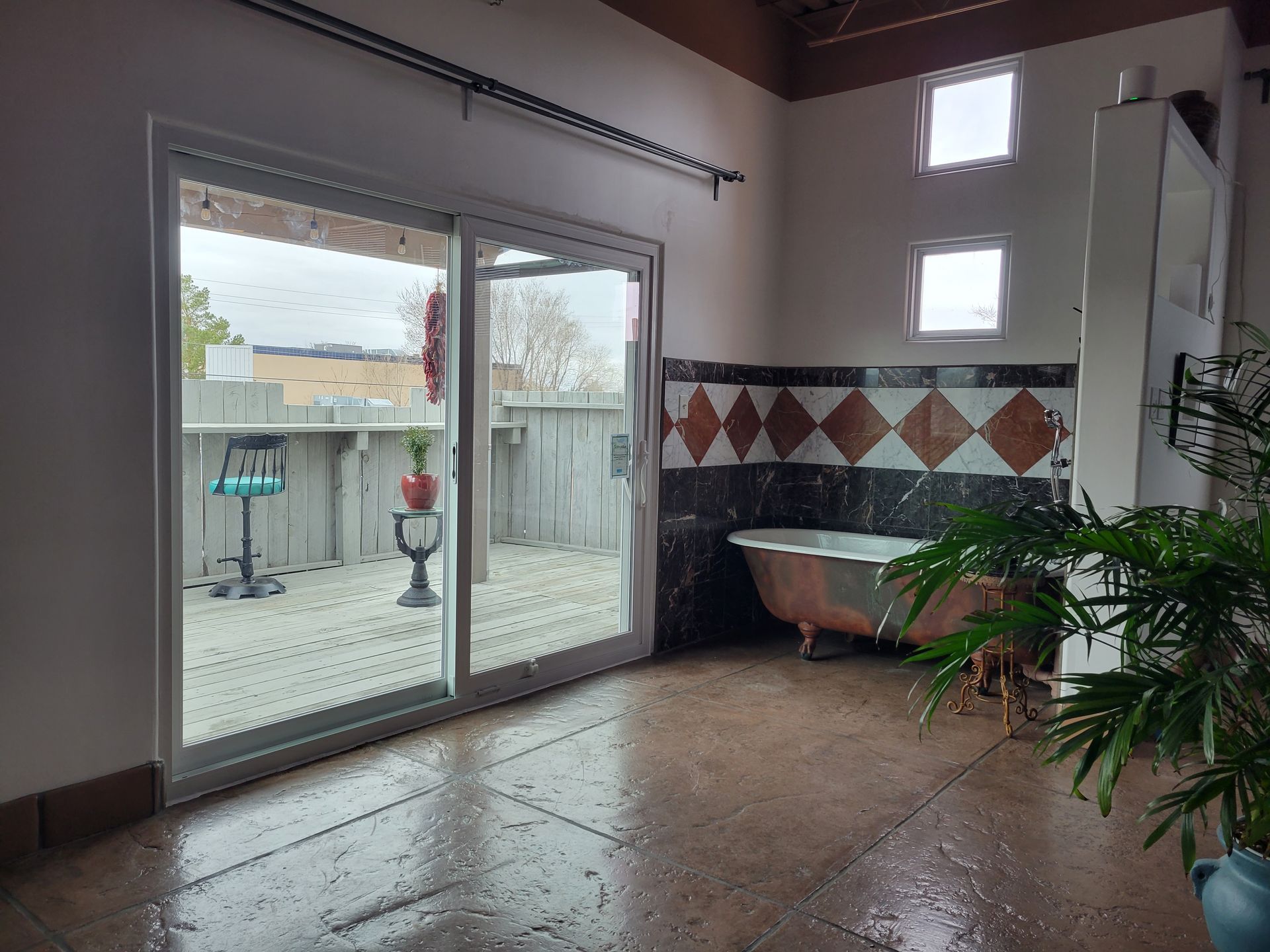 Bathroom with a vintage tub, sliding glass door to a deck, and tiled wall.