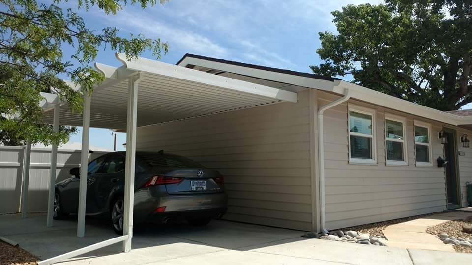 Carport attached to a beige house, with a silver car parked beneath.