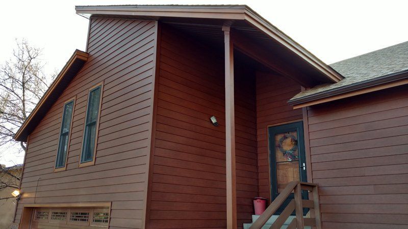 Brown house exterior with garage, door, and windows.