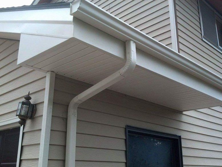 Tan siding with white gutter and soffit over a small entryway, with a downspout.