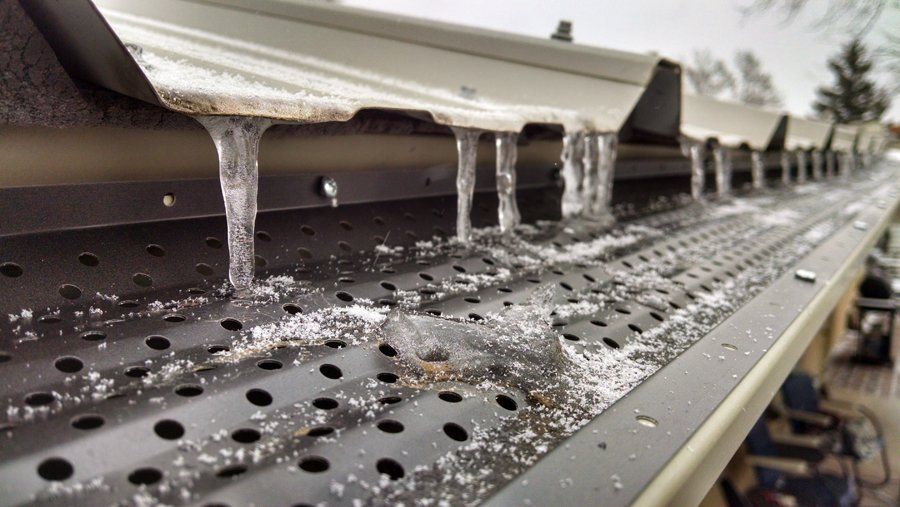 Icy gutters with icicles hanging; snow and ice on the metal surface.