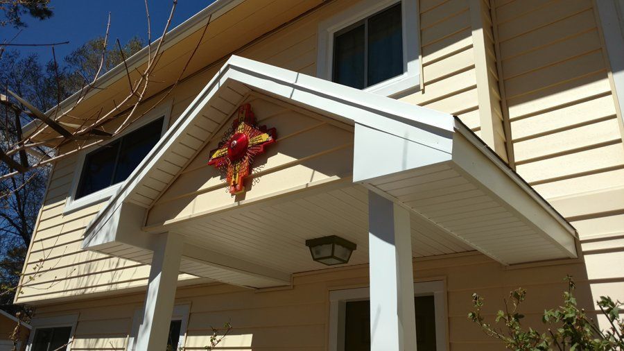 Yellow two-story house with white trim, porch, and a decorative sunburst.