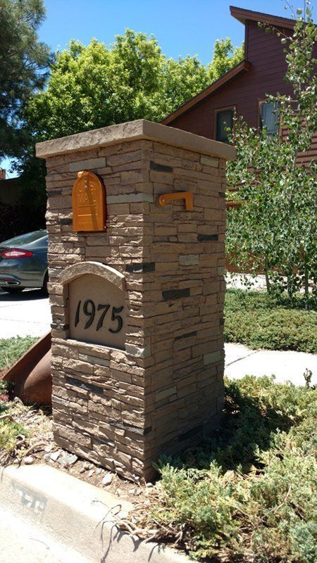 Stone pillar mailbox with gold mail slots and address 1975.
