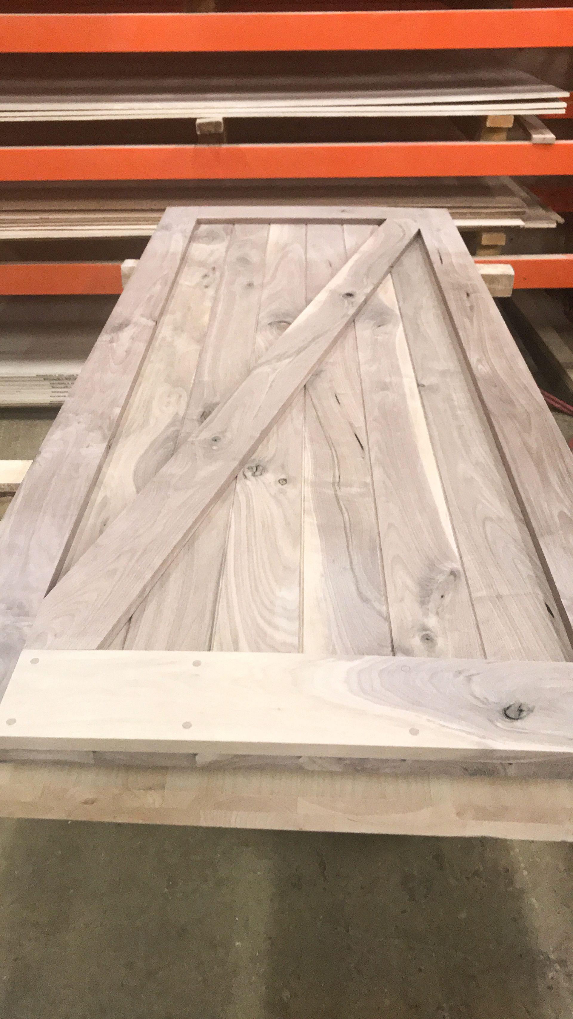 Wooden barn door with diagonal support, light wood color, resting on a table.