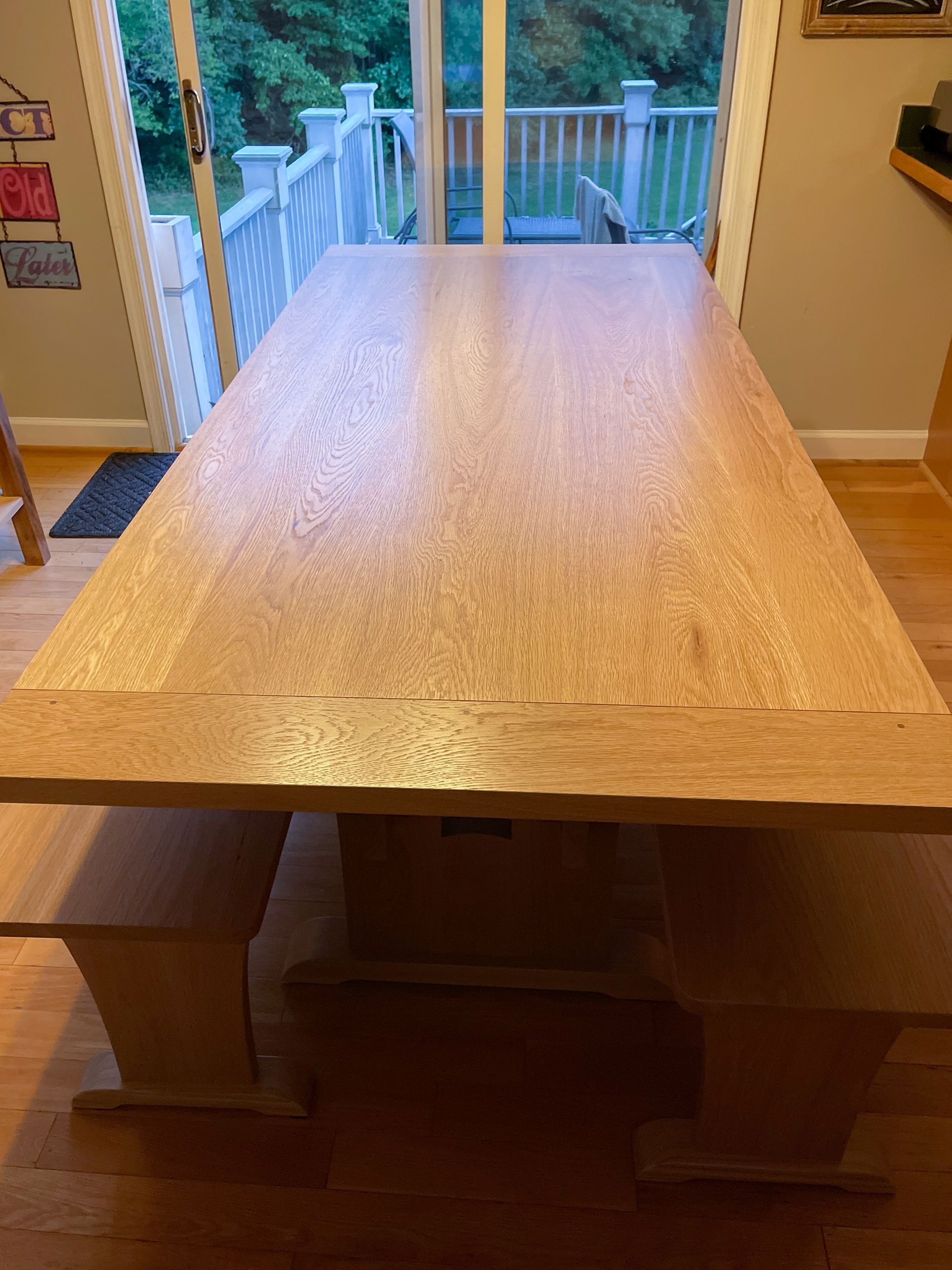 Wooden dining table with benches in front of a glass door.