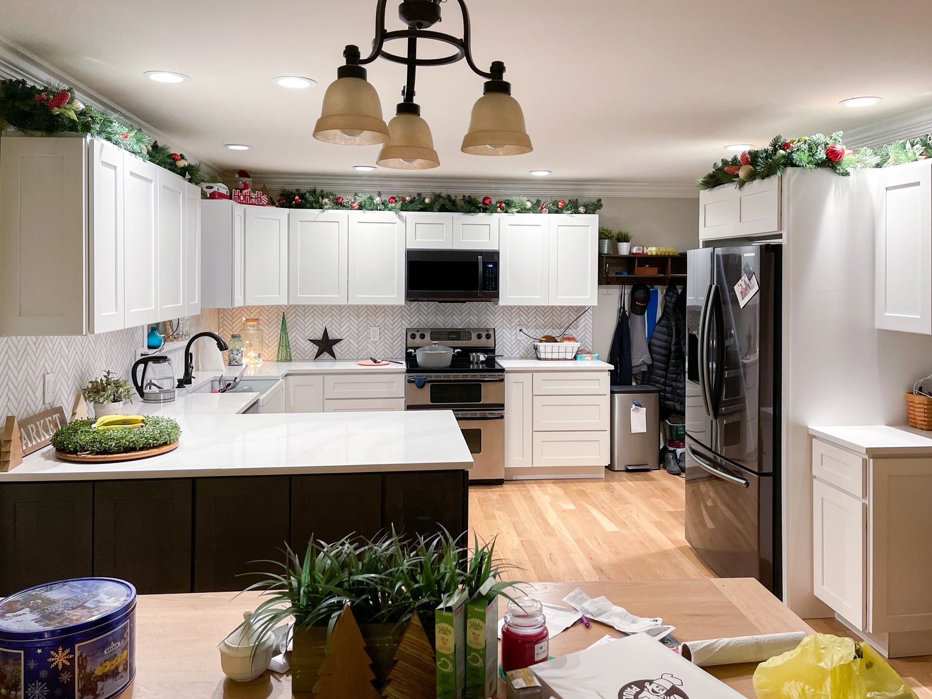 Kitchen with white cabinets, dark island, stainless steel appliances, and Christmas garland.