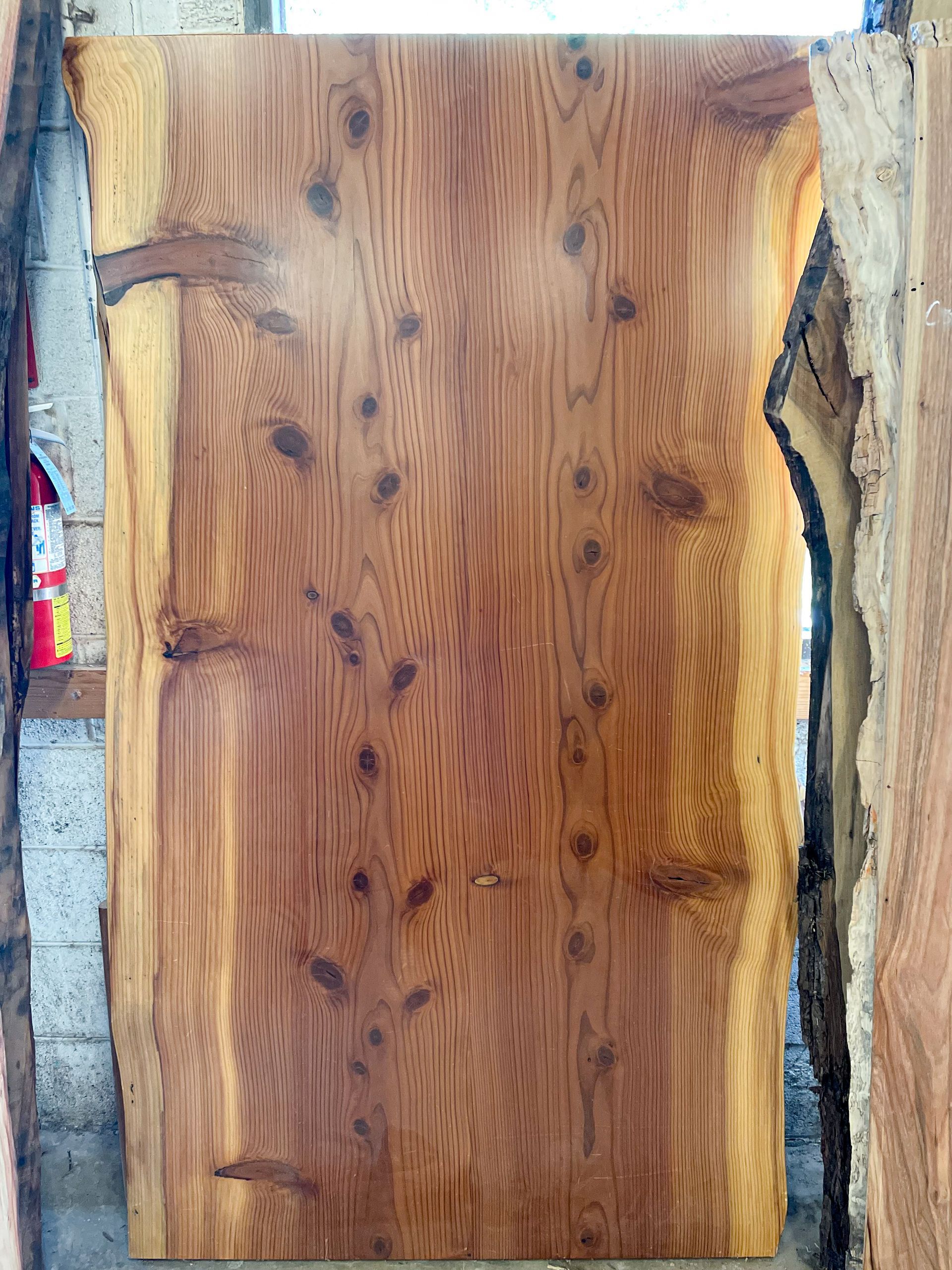 Large, rectangular slab of wood with knots and grain. Warm brown color with lighter edges.