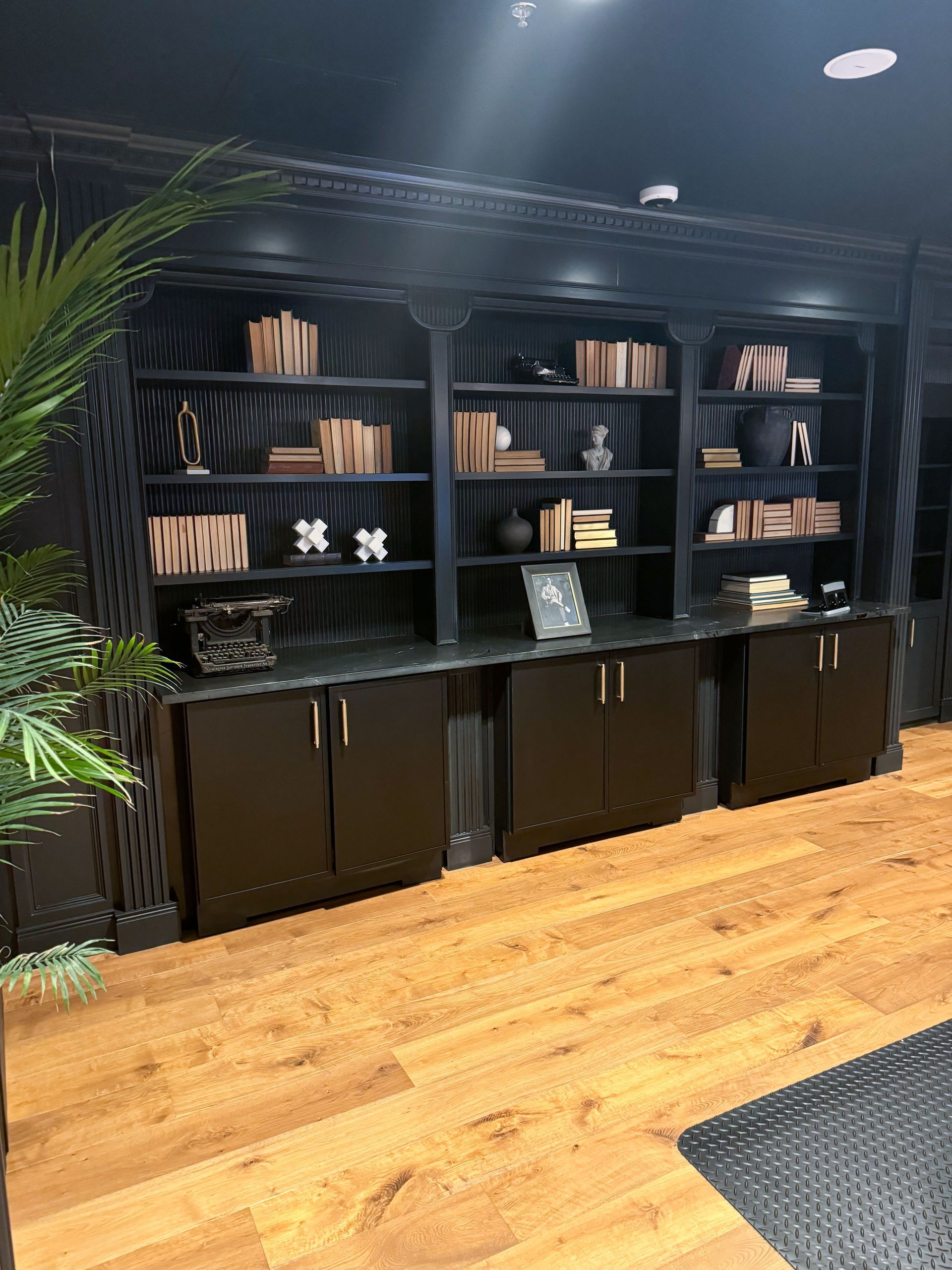 Built-in black bookshelves with wooden floors, filled with books and decor.