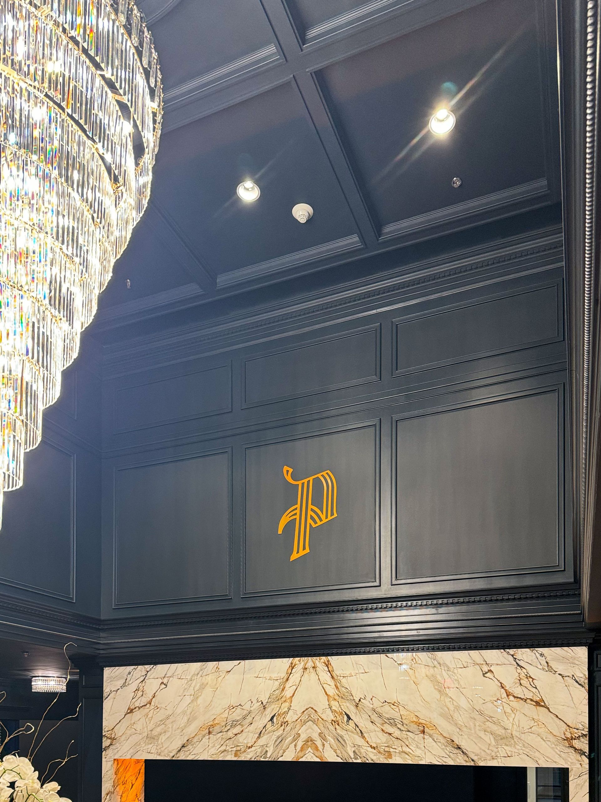 Black paneled wall with a gold letter 