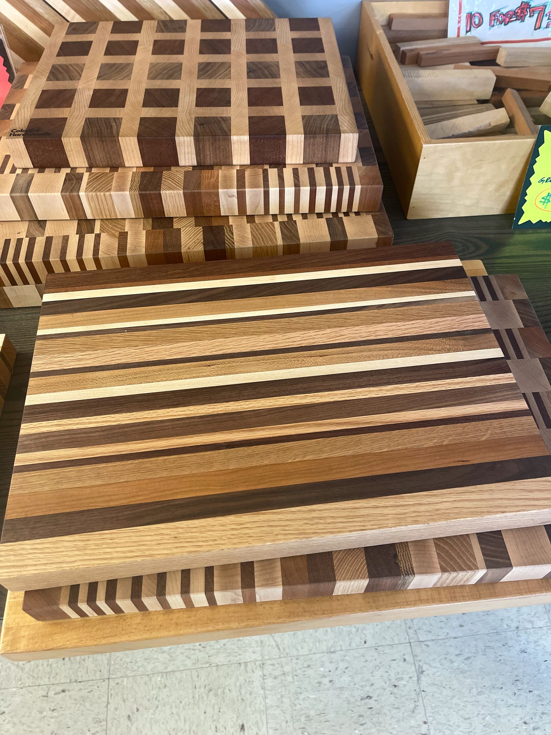 Wooden cutting boards stacked on a surface, various wood colors and patterns.