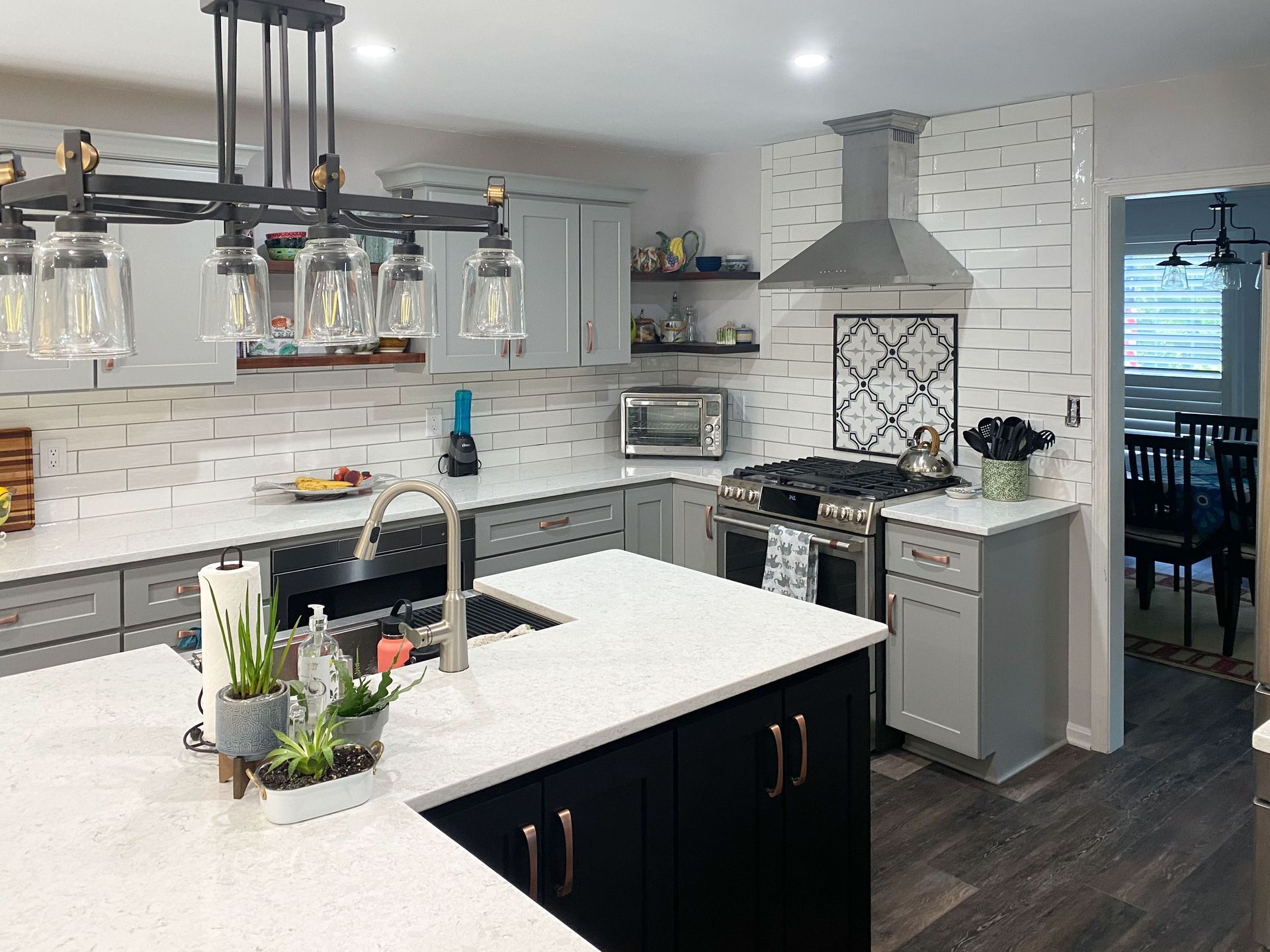 Modern kitchen with gray cabinets, white countertops, black island, and stainless steel appliances.