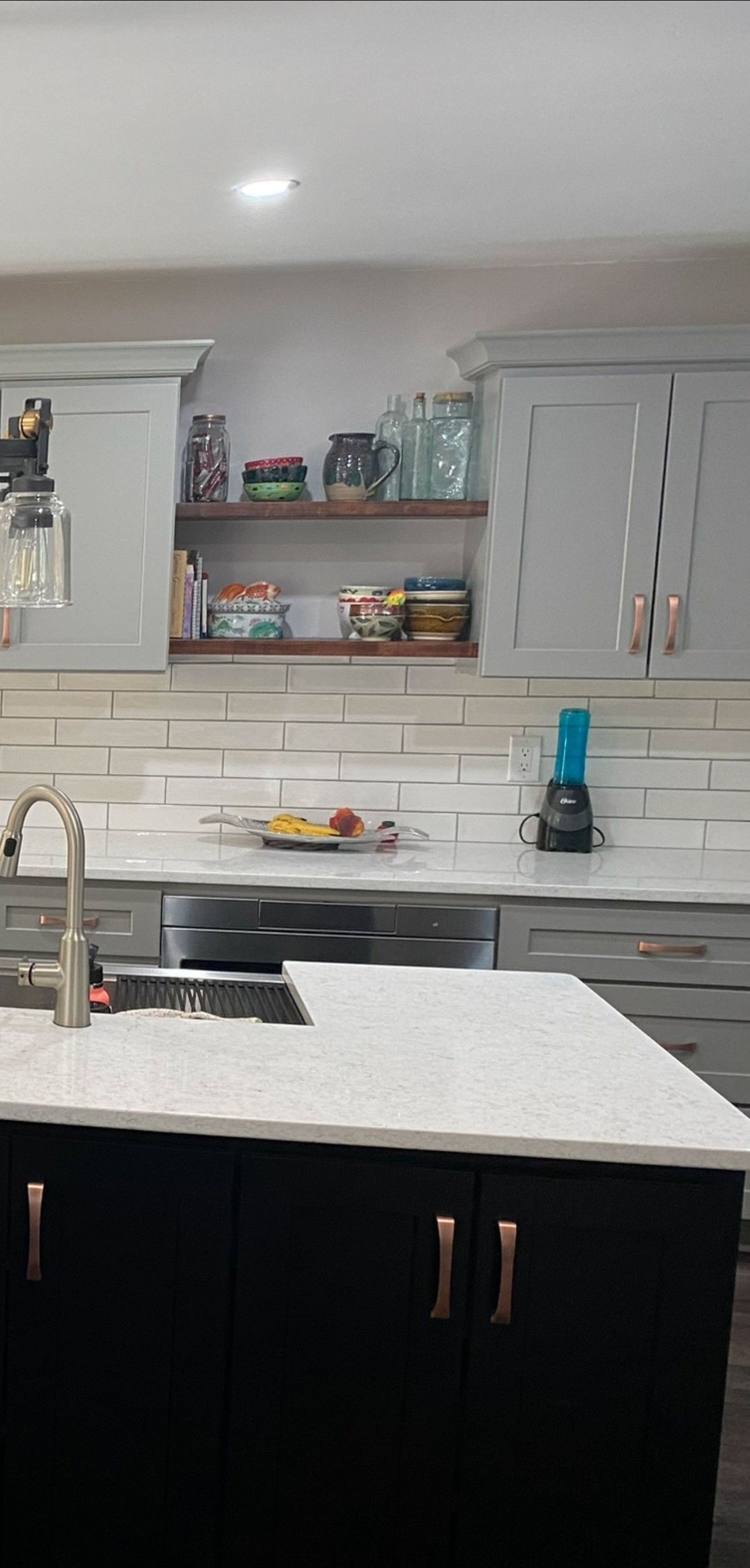 Kitchen with gray cabinets, white countertops, and a black island.