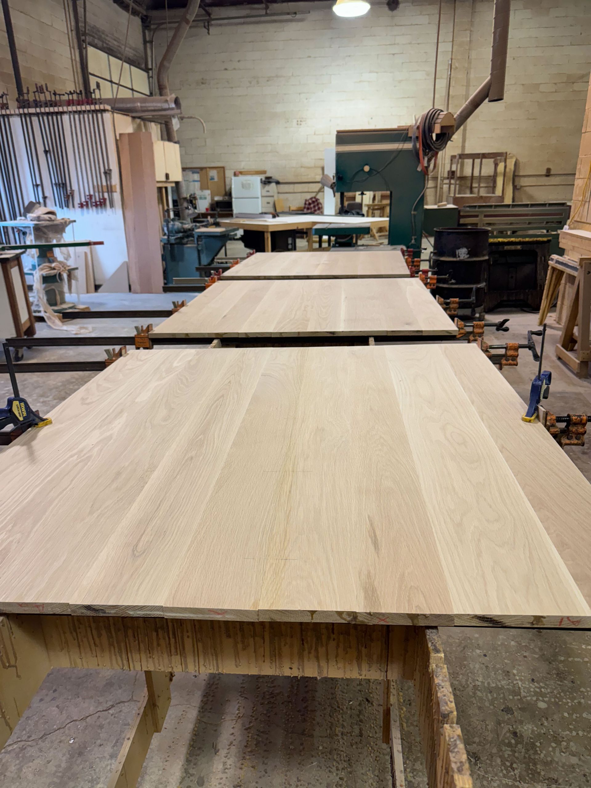 Three wooden tabletops clamped and drying in a workshop.