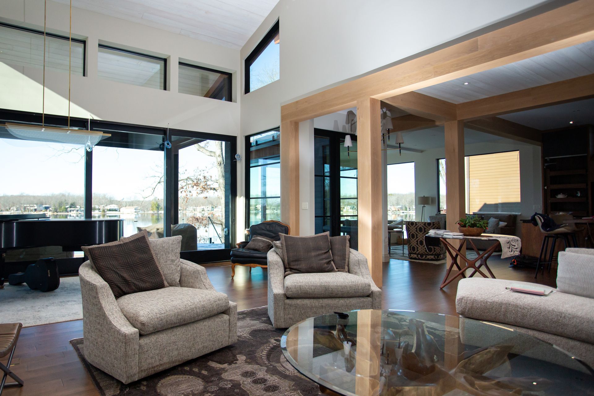 Living room with large windows, several armchairs, wooden beams, and an open layout with a view.
