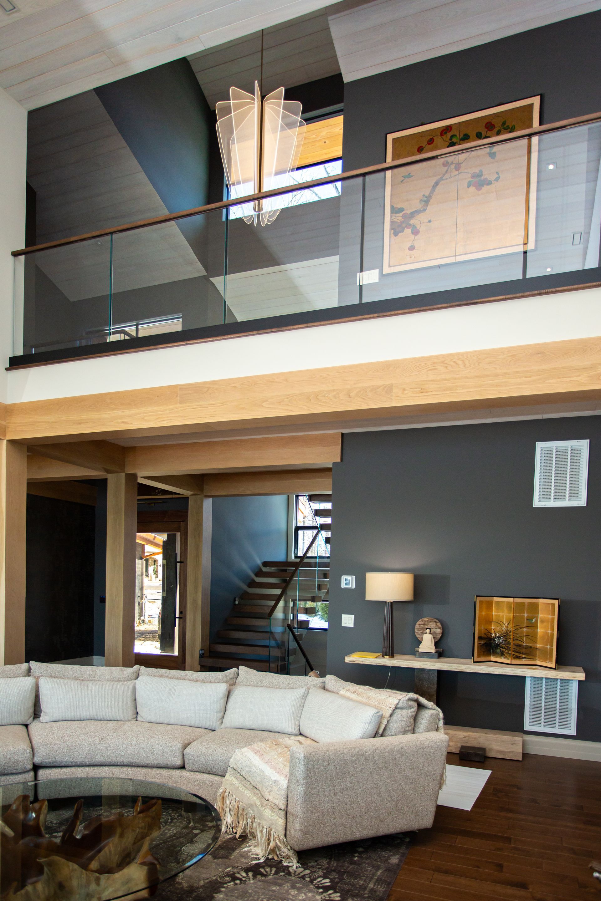 Living room with a modern loft: gray walls, wooden beams, a sectional sofa, and a map.