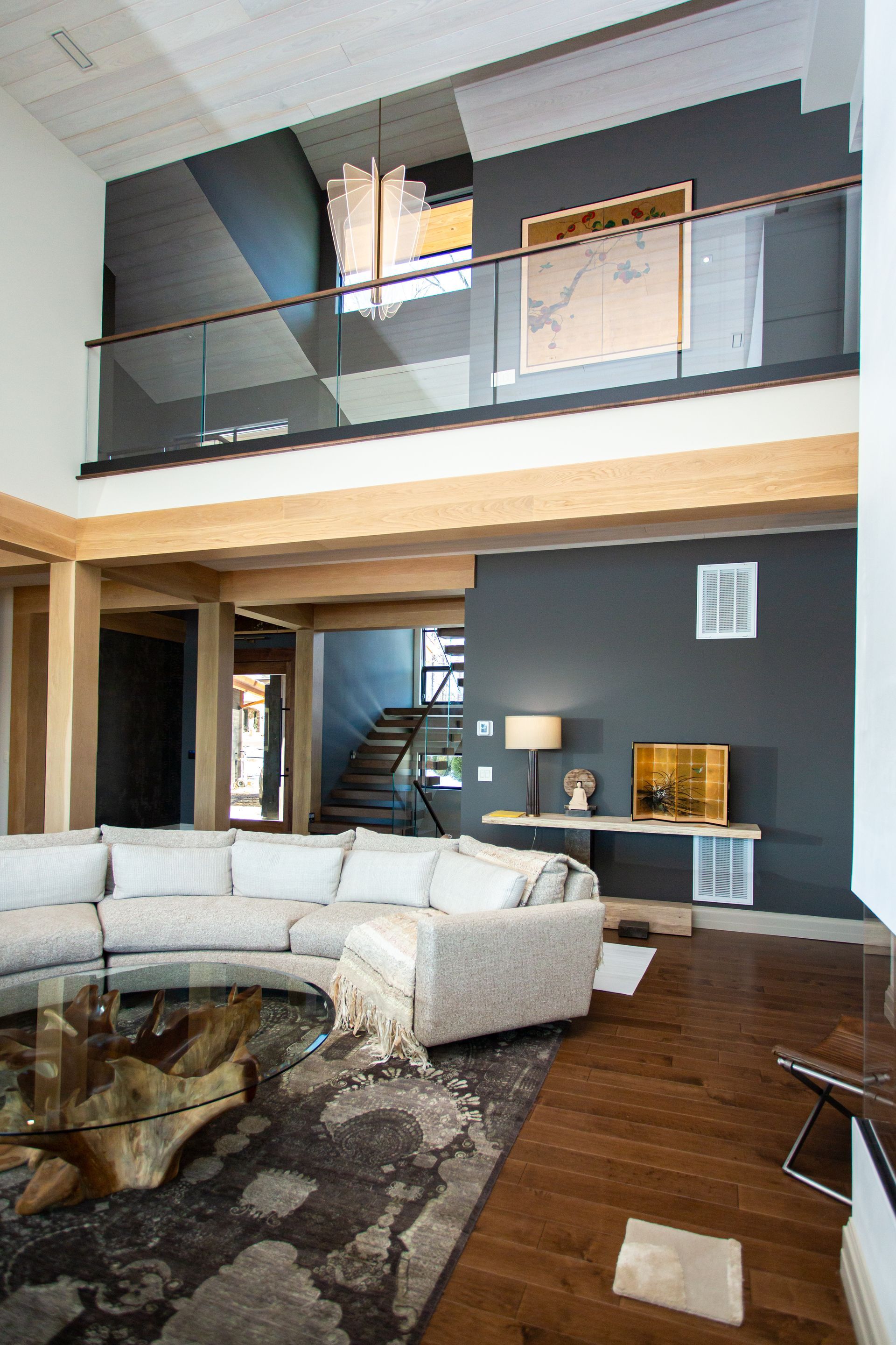 Living room with modern design: sectional sofa, dark accent wall, wood floors, and a balcony.