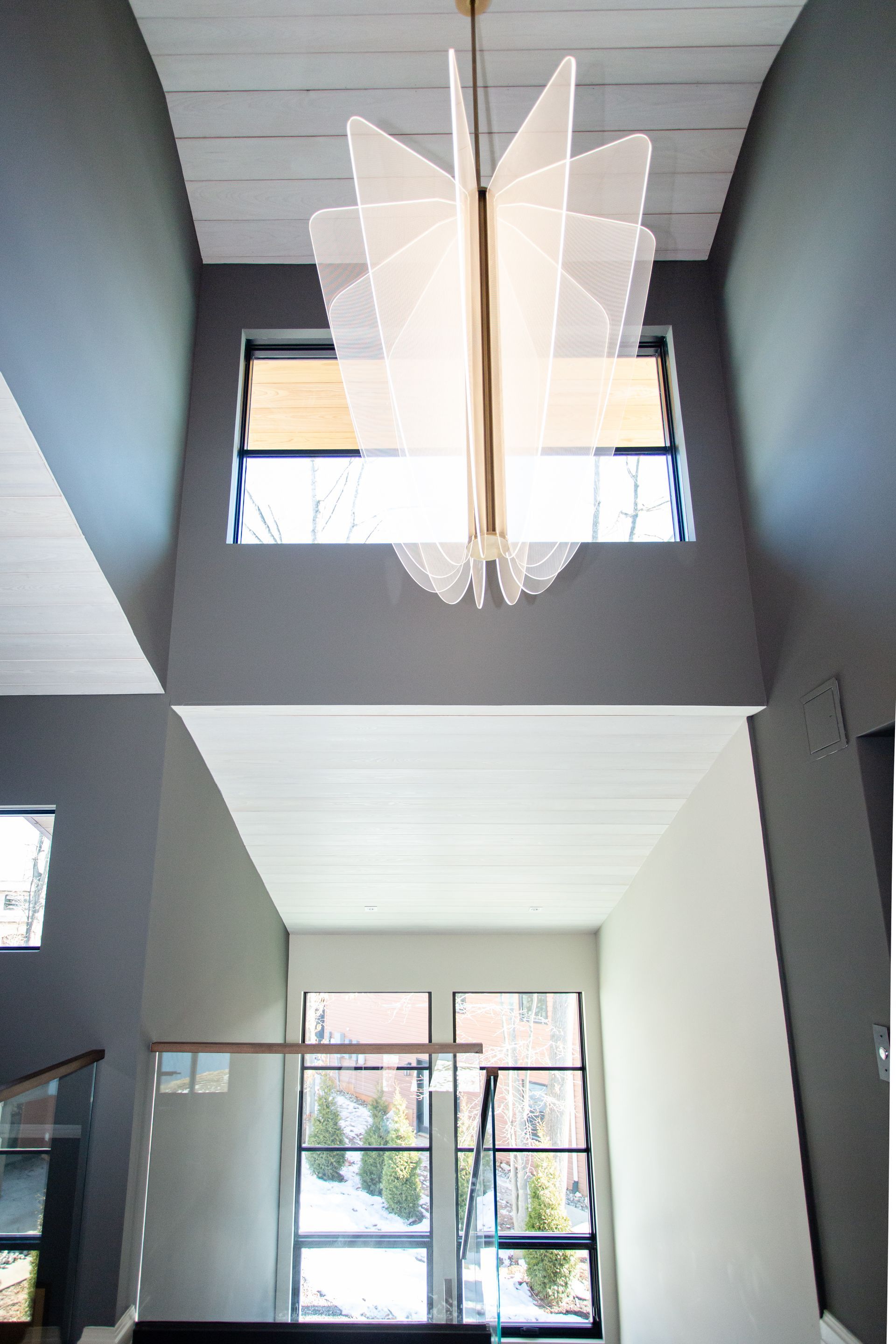 Modern entryway with gray walls, white ceiling, and a large geometric light fixture.