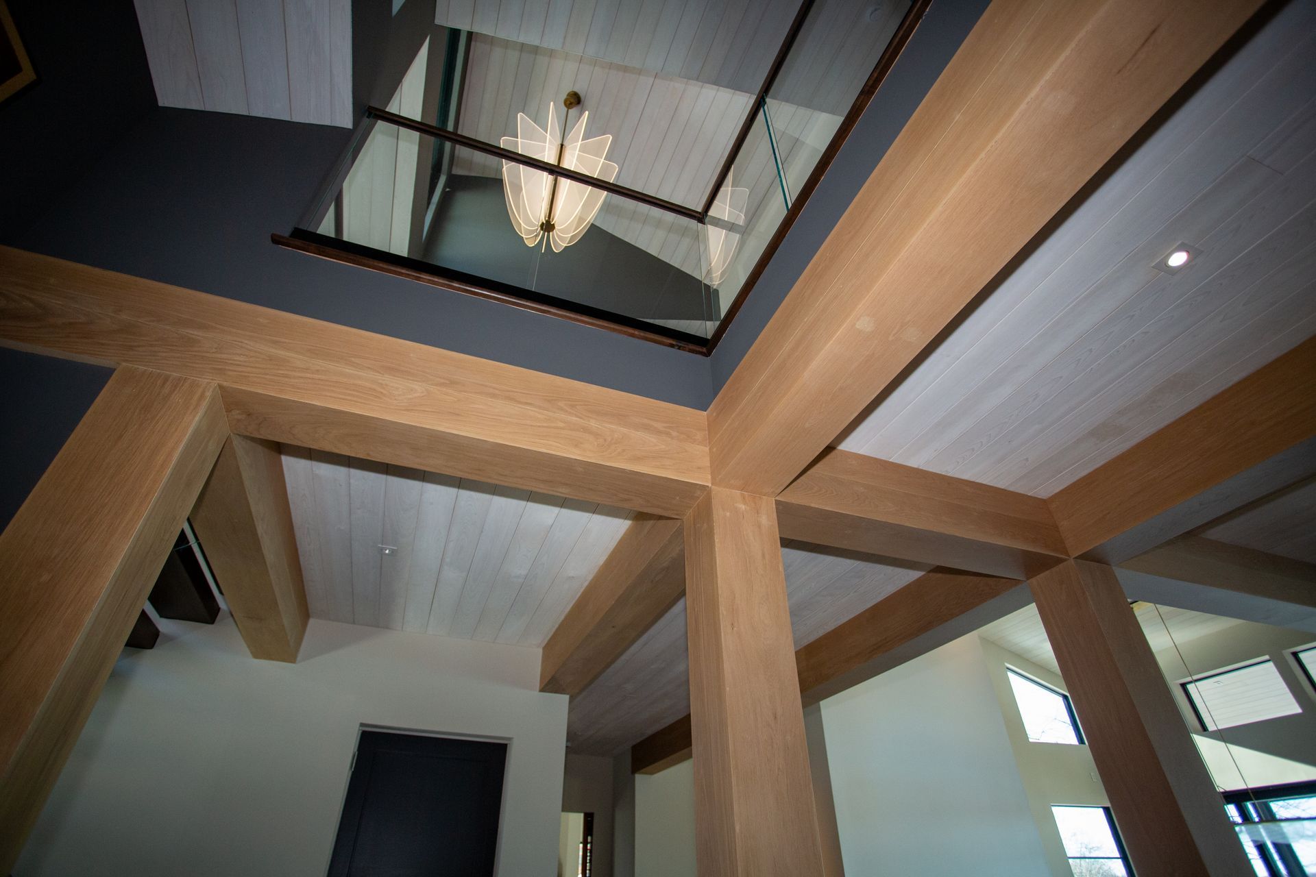 Interior view of a modern home with wood beams, a skylight, and a chandelier.