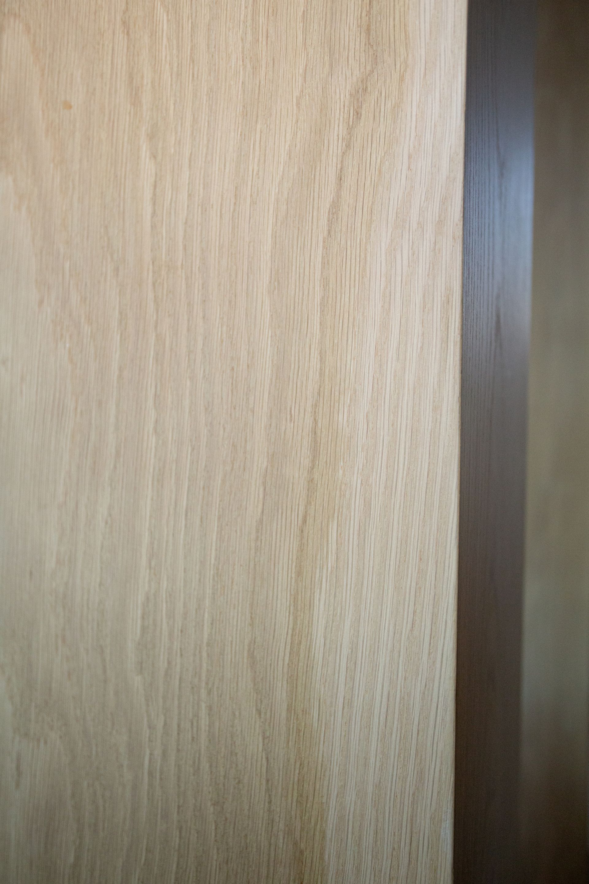Close-up of light-colored wood grain, vertical orientation, with a darker wood edge on the right.