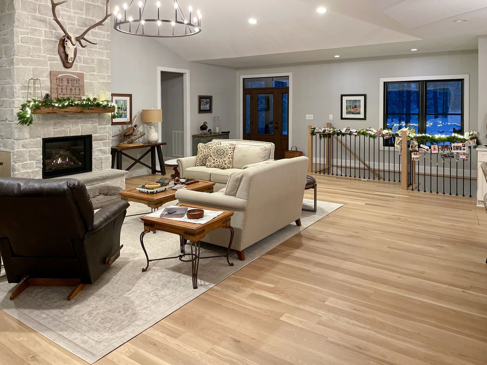Living room with fireplace, sofas, and wood flooring, decorated for the holidays.